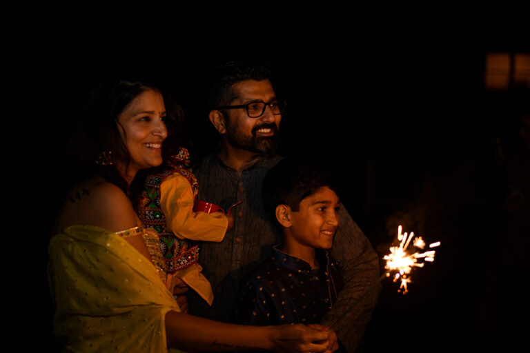 Family celebrating Diwali with sparklers outdoors after sunset